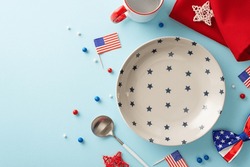 Fourth Of July-inspired Table Arrangement. Top View Of Patriotic Elements Like Dish, Utensils, Mug, Napkin, Sprinkles, Rattan Stars, Bow-tie, Flags On Pastel Blue Backdrop. Ample Space For Text Or Ads