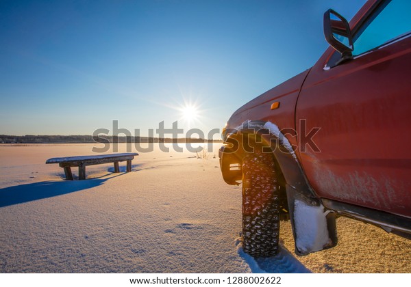 Four-wheel\
drive car front corner in Finland. The front sunlight shines\
brightly. There is winter and lots of\
snow.