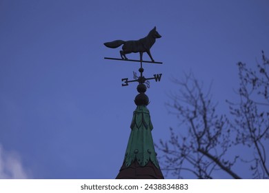 A fox weather vane, wind vane, or weathercock, showing the direction of the wind. This architectural ornament sits on the filial of a Victorian home.