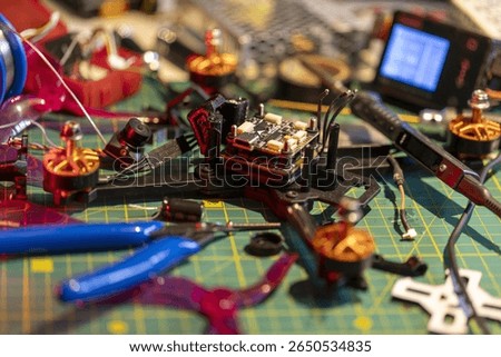 FPV drone assembly process with tools and electronic components on a workspace table is depicted. Concept of building and customizing drones for hobbyists and tech enthusiasts.