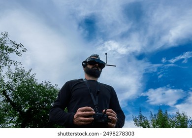 FPV drone man pilot photo outdoor blue sky. Mature bearded male copter vr operator teaching to fly in aircraft school - Powered by Shutterstock