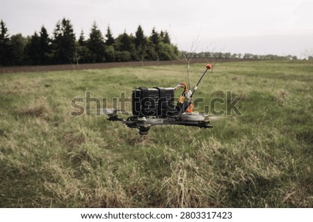 Fpv drone performing a test flight over a grassy field, preparing for military applications and reconnaissance missions