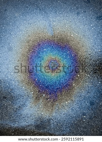 A fractal pattern on the asphalt surface created by a fuel spill from a parked car. I can tell it looks like a colored blue eye.