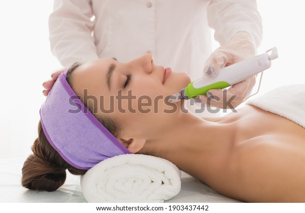 Fractional mesotherapy.A young beautiful\
woman in the cosmetologist’s office receives fractional mesotherapy\
for her face. Facial skin rejuvenation. Acne treatment. Hardware\
cosmetology.\
Beautician.