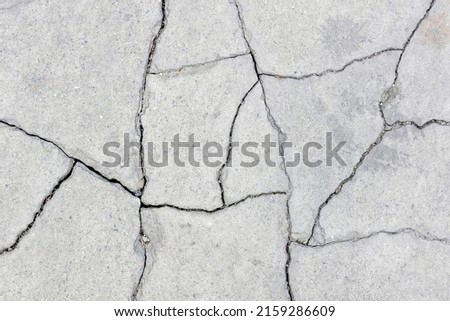 fractured concrete sidewalk floor, gray grunge cement surface cracked into pieces , earthquake effect causes ground to damaged, abstract texture background, close-up top view