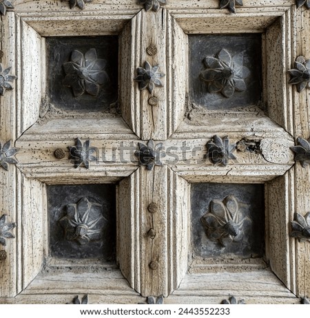 fragment of antique old door made of light unpainted wood and metal materials with floral pattern, close up. Elements of architecture aged buildings, shutters on windows