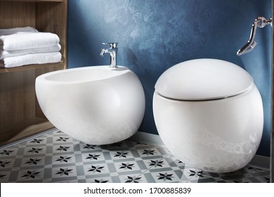 Fragment of bathroom interior: toilet and bidet. White bidet and toilet on blue wall