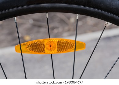 Fragment of bicycle wheel with plastic reflector orange color installed between the spokes
