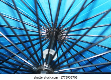 A Fragment Of A Blue Open Umbrella From The Inside. Umbrella With Black Knitting Needles And A Handle. Close-up.