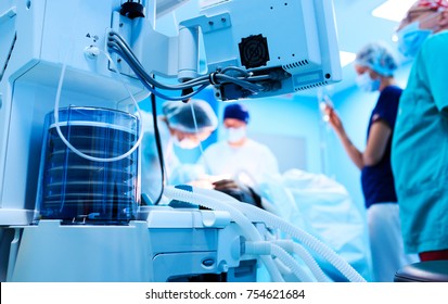 Fragment of breathing apparatus in the operating room, blurred background with team surgeon at work in hospital during their work. 