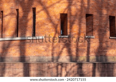 Fragment of a brick wall surrounding a military fortress from tsarist times, shadows of trees on the wall, loopholes