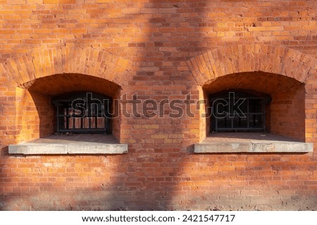 Fragment of a brick wall surrounding a military fortress from tsarist times, shadows of trees on the wall
