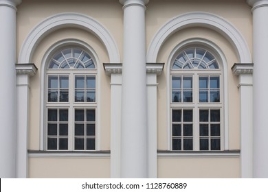 Fragment of the building façade with arched windows end white columns