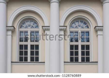 Fragment of the building façade with arched windows end white columns