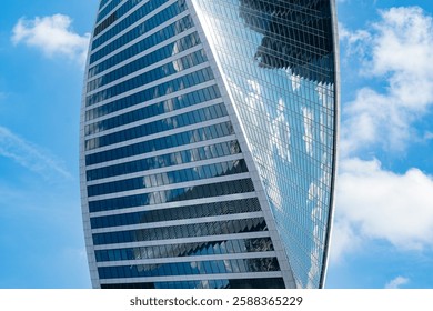 Fragment of a building and windows of a skyscraper. The Evolution Tower in the Moscow-City business center. Fragment of a spiral skyscraper against the sky.