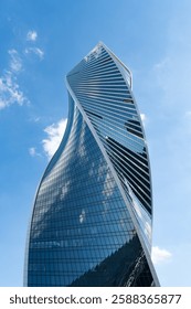 Fragment of a building and windows of a skyscraper. The Evolution Tower in the Moscow-City business center. Fragment of a spiral skyscraper against the sky.