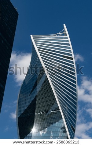 Fragment of a building and windows of a skyscraper. The Evolution Tower in the Moscow-City business center. Fragment of a spiral skyscraper against the sky.