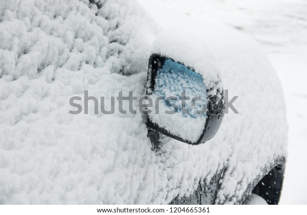 Fragment of car with mirror covered snow during the\
blizzard. Winter time.\
