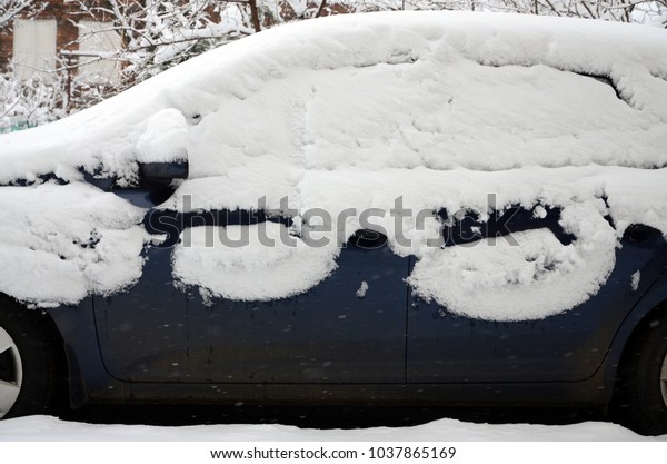 Fragment of the car\
under a layer of snow after a heavy snowfall. The body of the car\
is covered with white\
snow