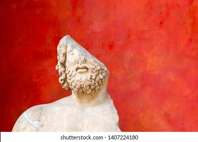 Fragment of a damaged antique sculpture against red background. Half a man. Incomplete or something missing concept. Copy space.