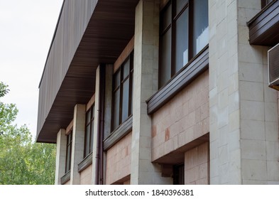 Fragment Facade Of Sports Complex Building With Columns And Windows. Building Is Faced With Rectangular Stone Slabs. Contemporary Architecture