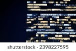 Fragment of the glass facade of a modern corporate building at night. Modern glass office  in city. Big glowing windows in modern office buildings at night, in rows of windows light shines. 