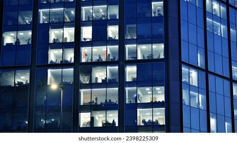 Fragment of the glass facade of a modern corporate building at night. Modern glass office  in city. Big glowing windows in modern office buildings at night, in rows of windows light shines.  - Powered by Shutterstock