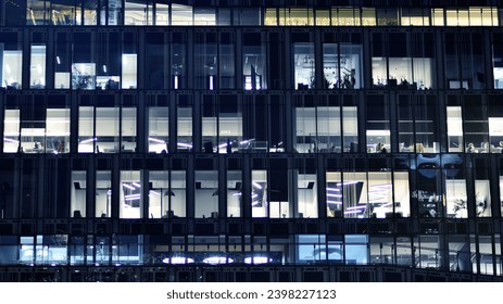 Fragment of the glass facade of a modern corporate building at night. Modern glass office  in city. Big glowing windows in modern office buildings at night, in rows of windows light shines.  - Powered by Shutterstock