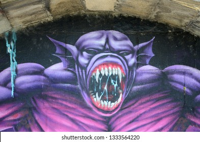 Fragment of graffiti drawings. The old wall decorated with paint stains in the style of street art culture. Purple scary monster