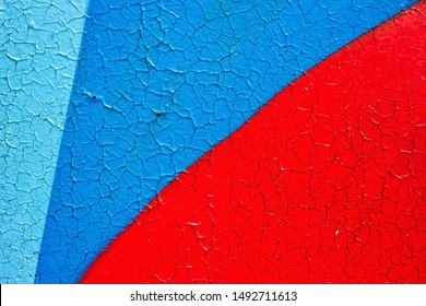 Fragment of graffiti drawings. Old wall decorated with blue red paint stains in style street art culture. Peeling paint on colored background. Grunge cracks effect texture, cracked concrete rough wall