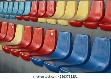 A fragment of the grandstand of an sports stadium with multi-colored seats.  - Shutterstock ID 2363782251