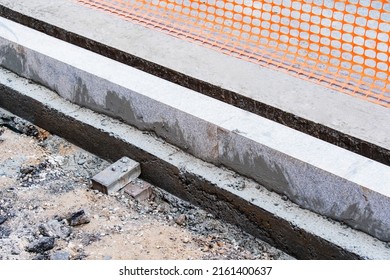 A Fragment Of A Granite Curb Installed On The Edge Of The Road. Construction Of Roads And Sidewalks On A City Street. Close-up.