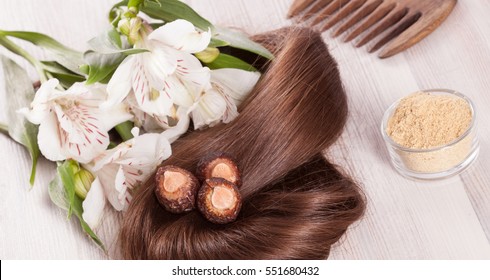 Fragment Of Healthy Shiny Woman Hair And Natural Products For Haircare; Closeup Of Woman Hair, Soapnuts, Ayurvedic Powder, Wooden Comb And Fresh Flowers