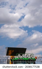 Fragment Of Heavy Machinery With Headlights On Cab And Bucket On Sky Background. Four Round Lights When Working At Night.