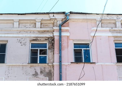 Fragment of a historic building with cracks and a shabby facade. Poor repair and painting of the wall. Close-up