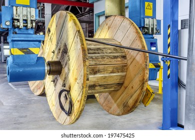 Fragment inside modern plant producing power electric cable, optical fiber. Interior of modern production line. Large wooden packing reels for transportation, sale of consumer power thick metal cable