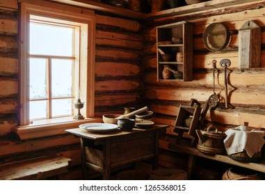 Fragment Of The Interior Of An Old Peasant Log Cabin - A Table With Wooden And Ceramic Dishes, A Kerosene Lamp