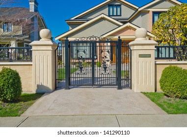 Fragment of the Luxury custom made house behind iron gates with long doorway at sunny day in Vancouver, Canada.