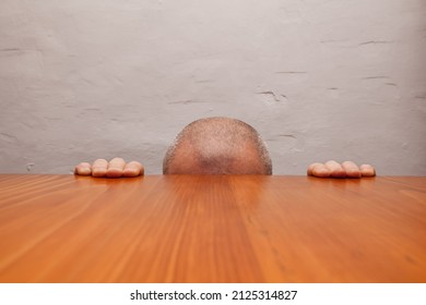 Fragment Of Male Head Extending Above Table Lines And Hands Leaning Against Edge Of Table.