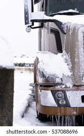 Fragment of modern coffee-colored truck covered with snow and ice
