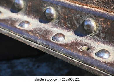A fragment of an old rusty metal I-beam with rivets. Metal detail riveted with rivets close-up. 