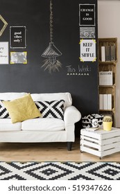 Fragment of optimistic living room with white sofa and motivational phrases on the wall