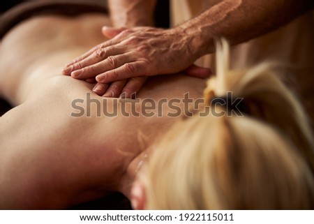 Fragment photo of a blonde lady with bare back getting a massage by professional masseur