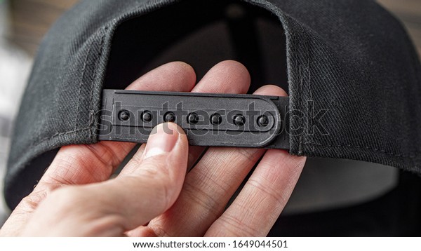 Fragment Of A Plastic Black Clasp Of A\
Baseball Cap In A Male Hand. The Concept Of Clothing And\
Accessories. Place For Advertising. High Quality\
Photo