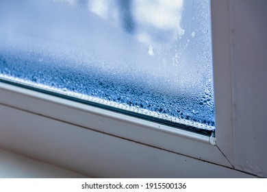 A fragment of a plastic window with condensation of water on the glass. Concept: defective plastic window with condensation, temperature difference, cooling, humidity in the room.