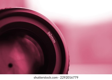 Fragment of a portrait lens for a modern SLR camera. A photograph of a wide-aperture lens with a focal length of 50mm Image toned in Viva Magenta, color of the 2023 year