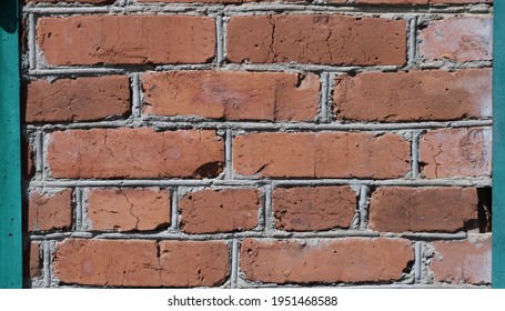 Fragment Of A Red Brick Wall In Combination With A Green Metal Frame, A Part Of A Block Facade Of An Old Building, A Brick Space With Painted Iron Inserts On The Sides, An Element Of An Odd Structure