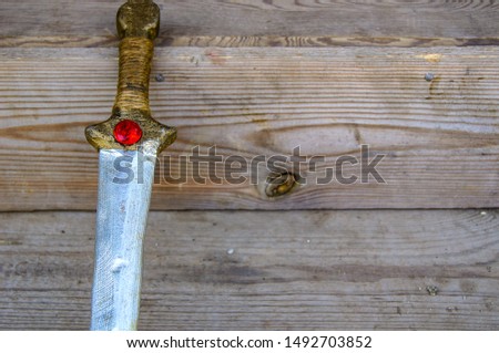 Fragment of a sword made of wood on the background of a wooden staircase.  Children's toy for self-defense training