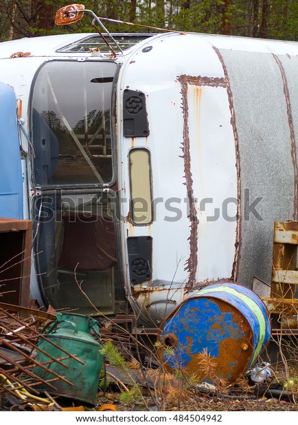 Fragment of trucking dump. Old bus and empty blue\
barrel out of fuel in\
forest