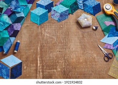 Fragment of tumbling blocks quilt, accessories for quilting on a wooden surface. Space for text.